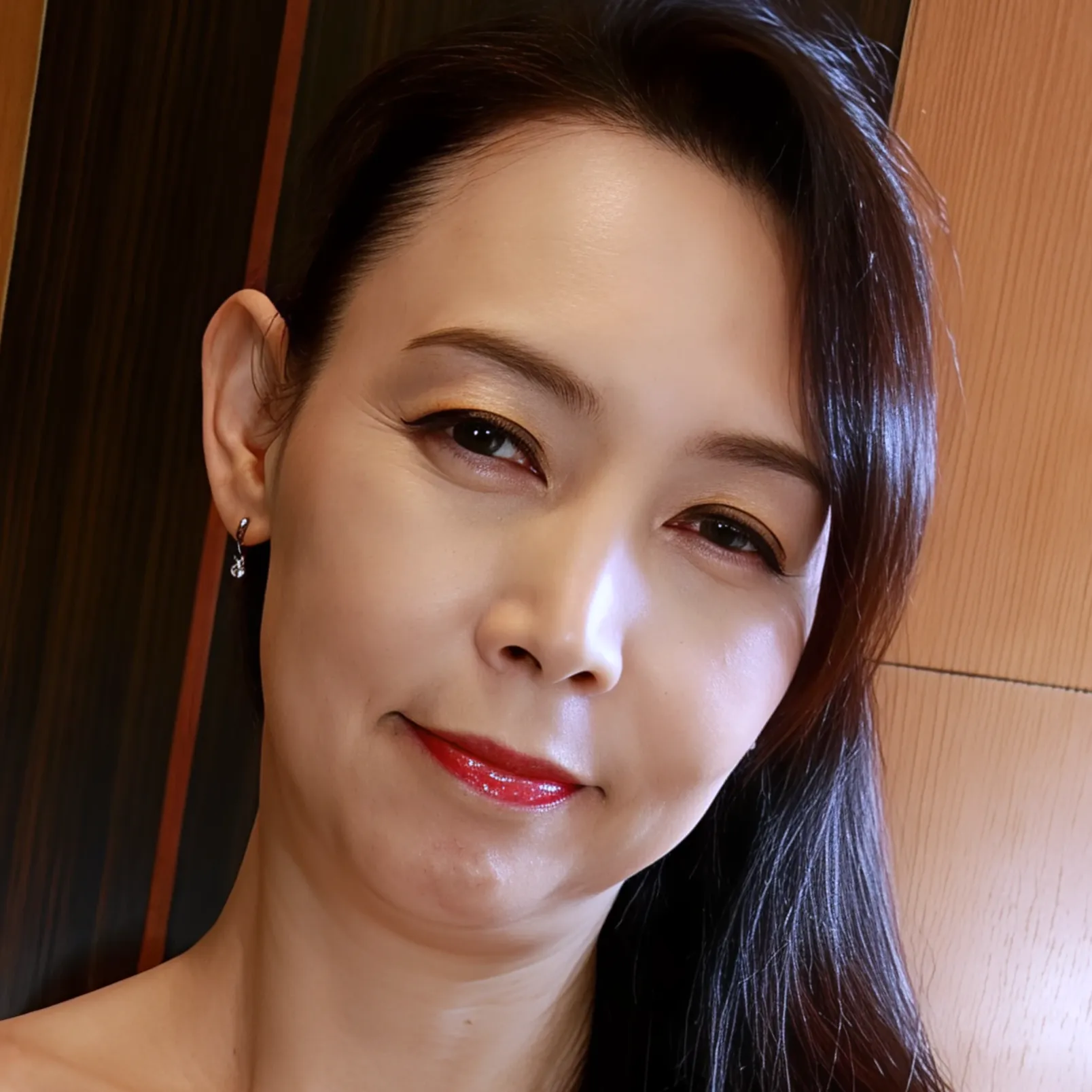 赤い口紅をつけ上品に微笑む55歳の女性、木並則子さんの写真